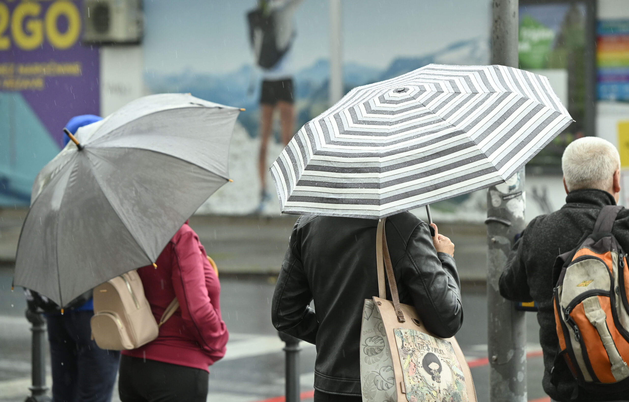 Čakanje na semaforju pod dežniki