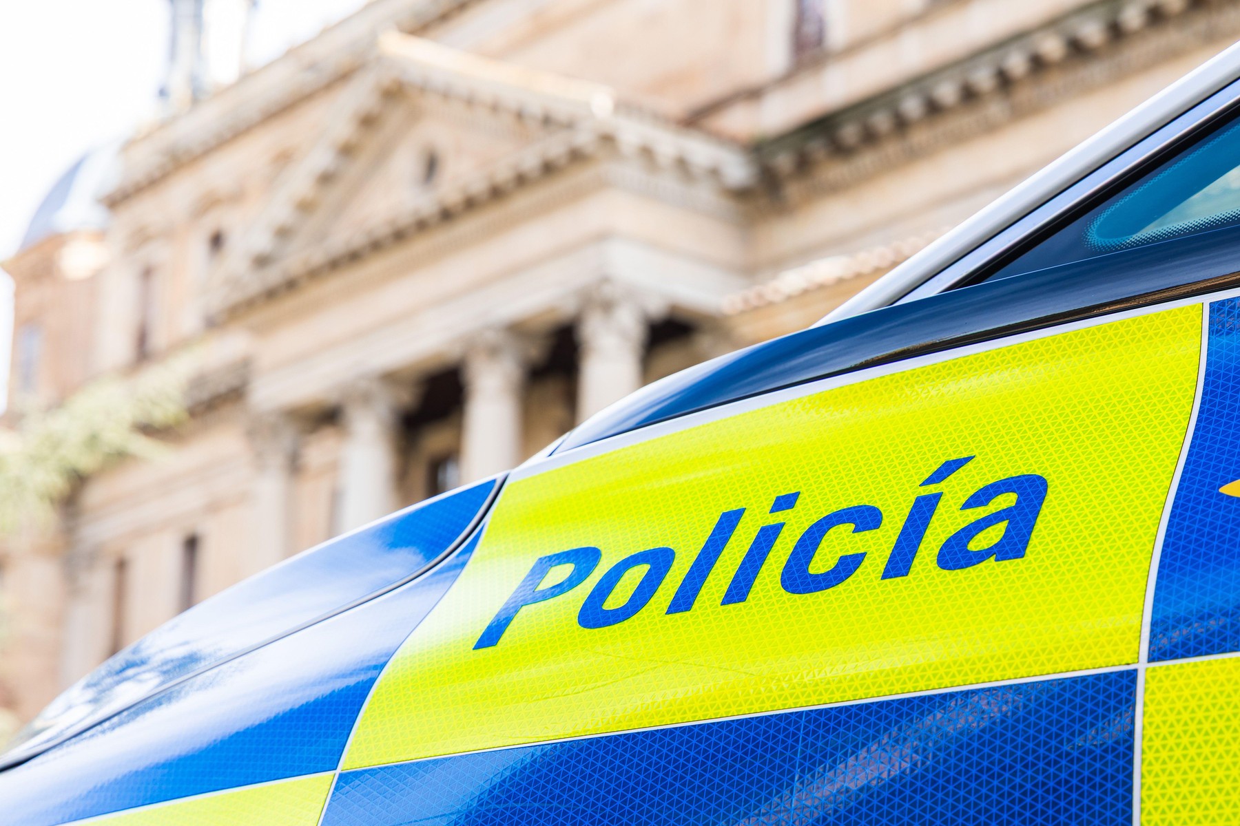 A close-up of a Spanish police car displaying the word "Policía" on its blue and yellow reflective markings