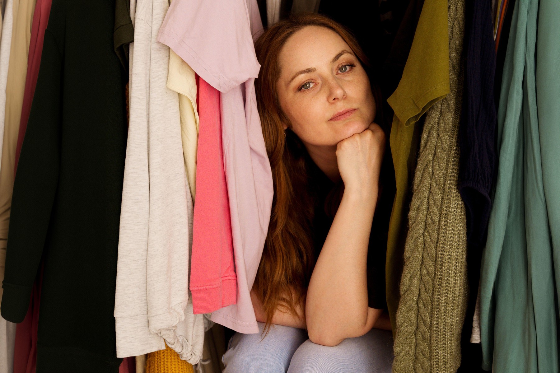 ženska, ki sedi med oblačili