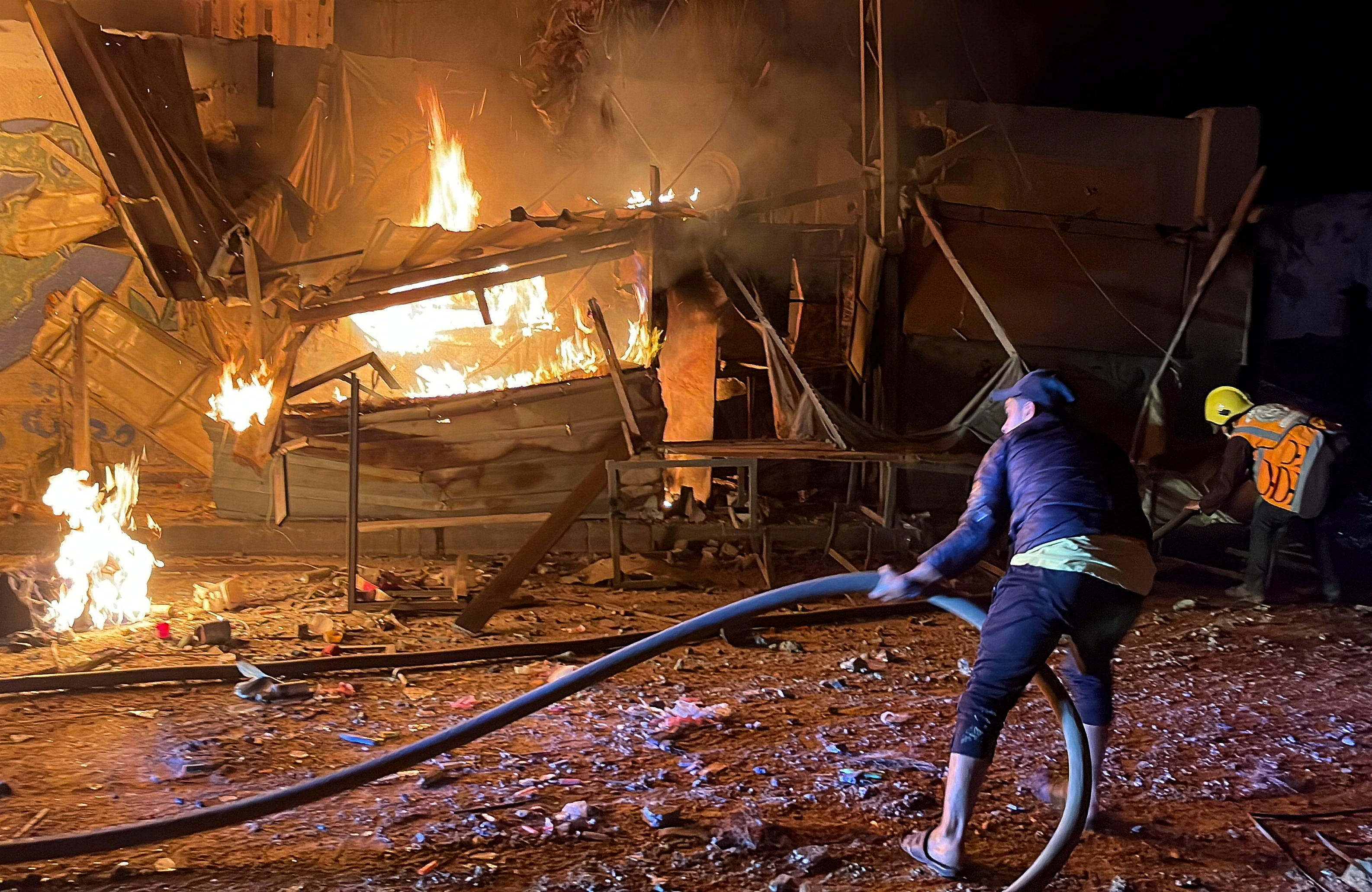Palestinci gasijo požar po izraelskem napadu na nekdanjo šolo v Gazi.