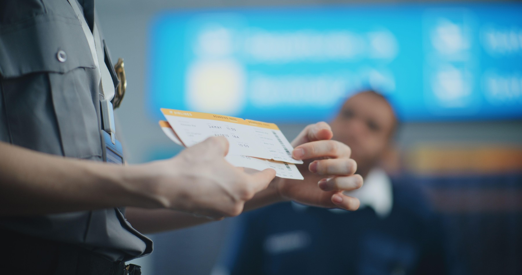 Letališka uslužbenka v roki drži letalsko vozovnico.