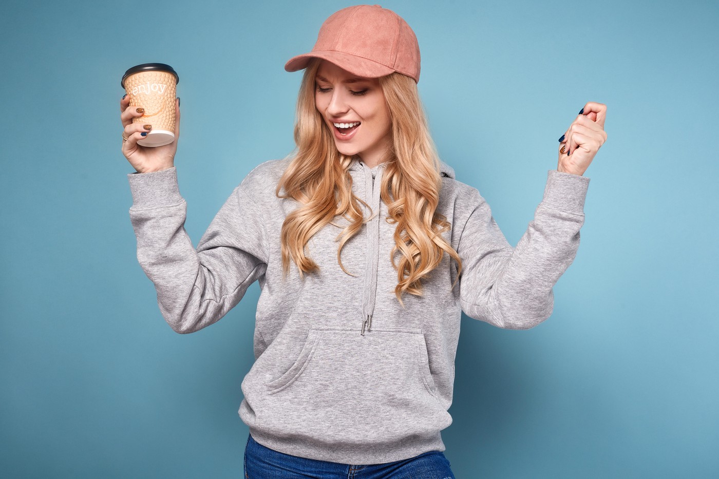 nasmejana ženska, ki v roki drži skodelico kave