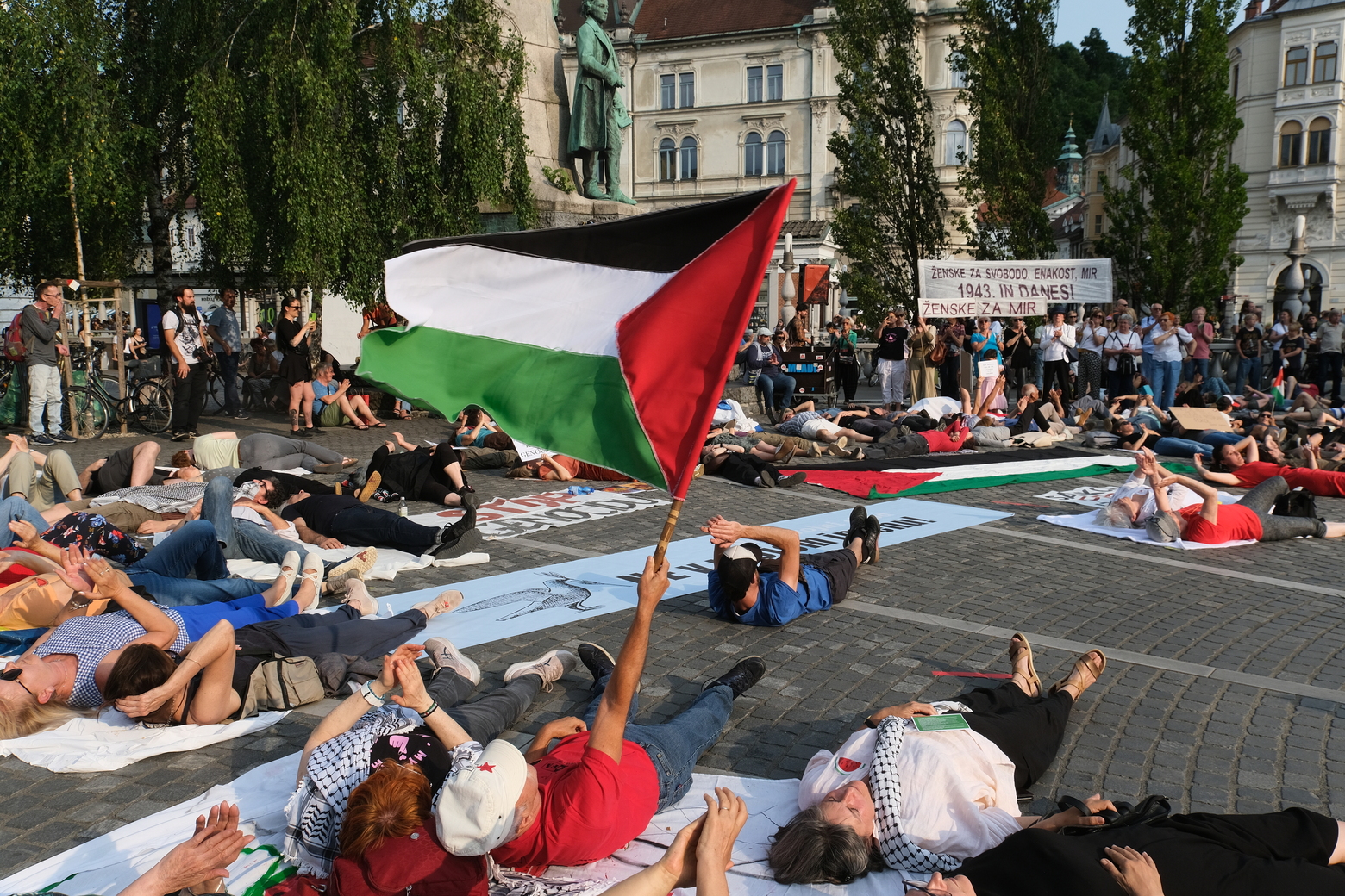 Ljudje ležijo na tleh v okviru protestnega shoda "Obležimo za Palestino"