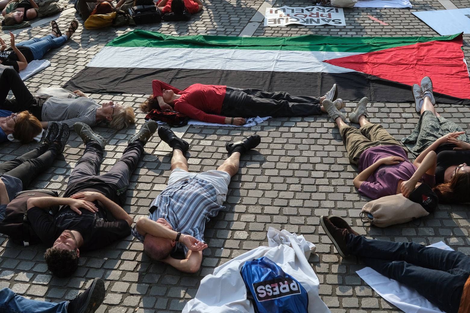 Ljudje ležijo na tleh v okviru protestnega shoda "Obležimo za Palestino"