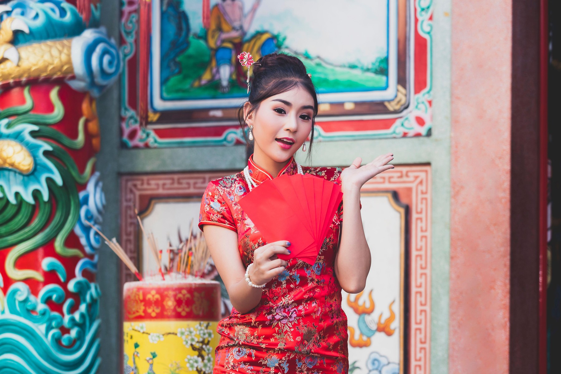 kitajka v tradicionalnih oblačilih in z rdečimi kuvertami