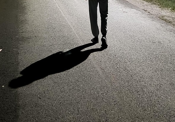 Moški, ki ponoči hodi po ulici.