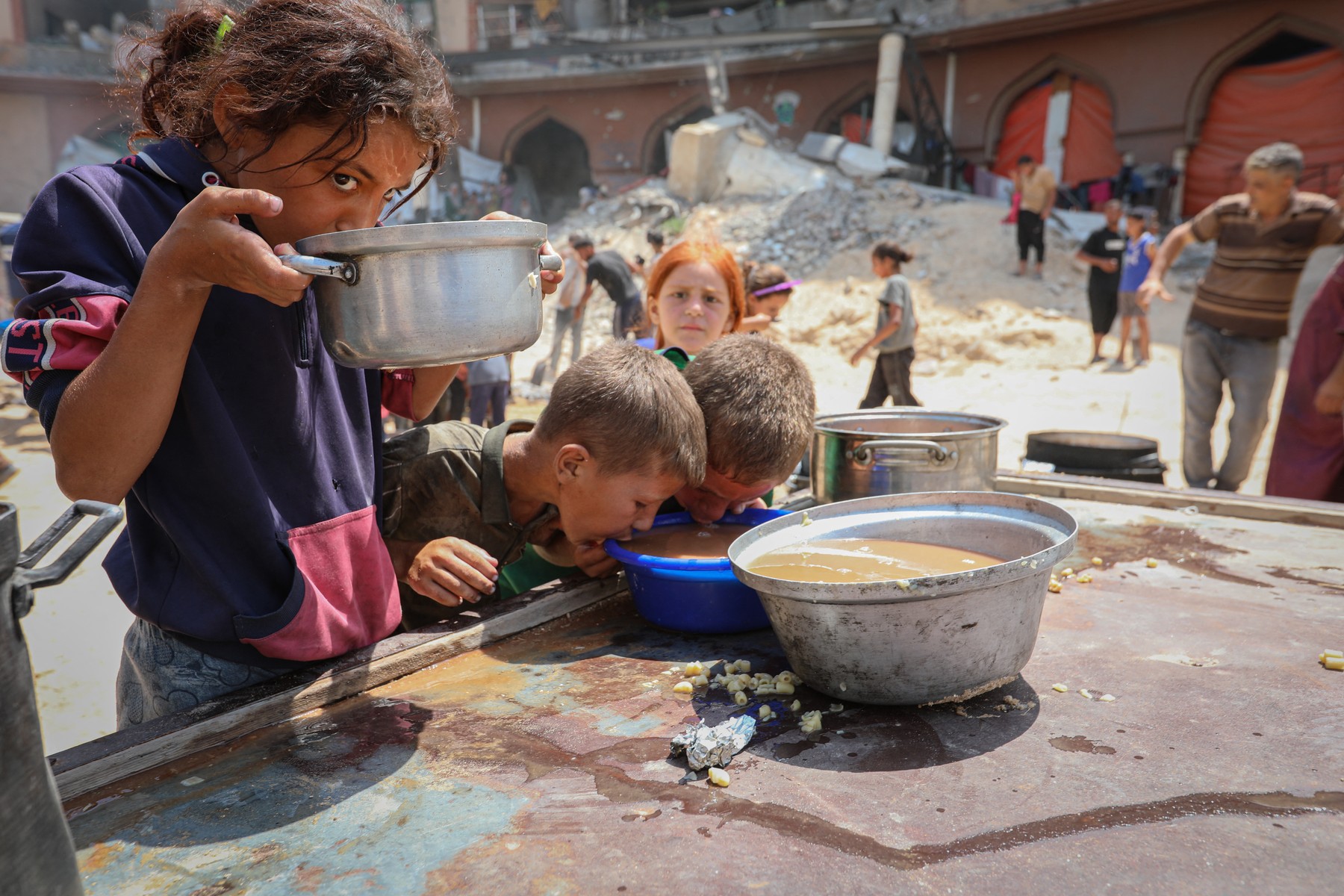 Otroci v mestu Gaza jedo juho, ki so jo dobili od humanitarnih organizacij