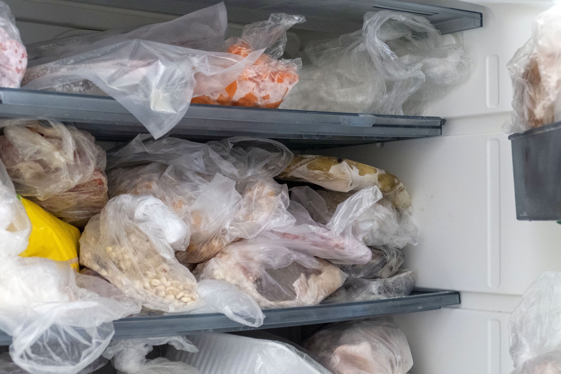Frozen foods are in a freezer with the door open,  a messy inside of a deep freezer,,Image: 673915041, License: Royalty-free, Restrictions: , Model Release: no