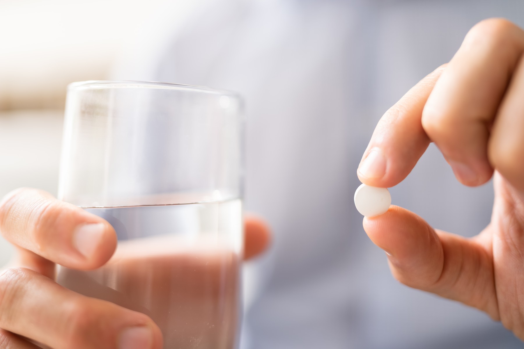 Moški jemlje zdravilo s kozarcem vode