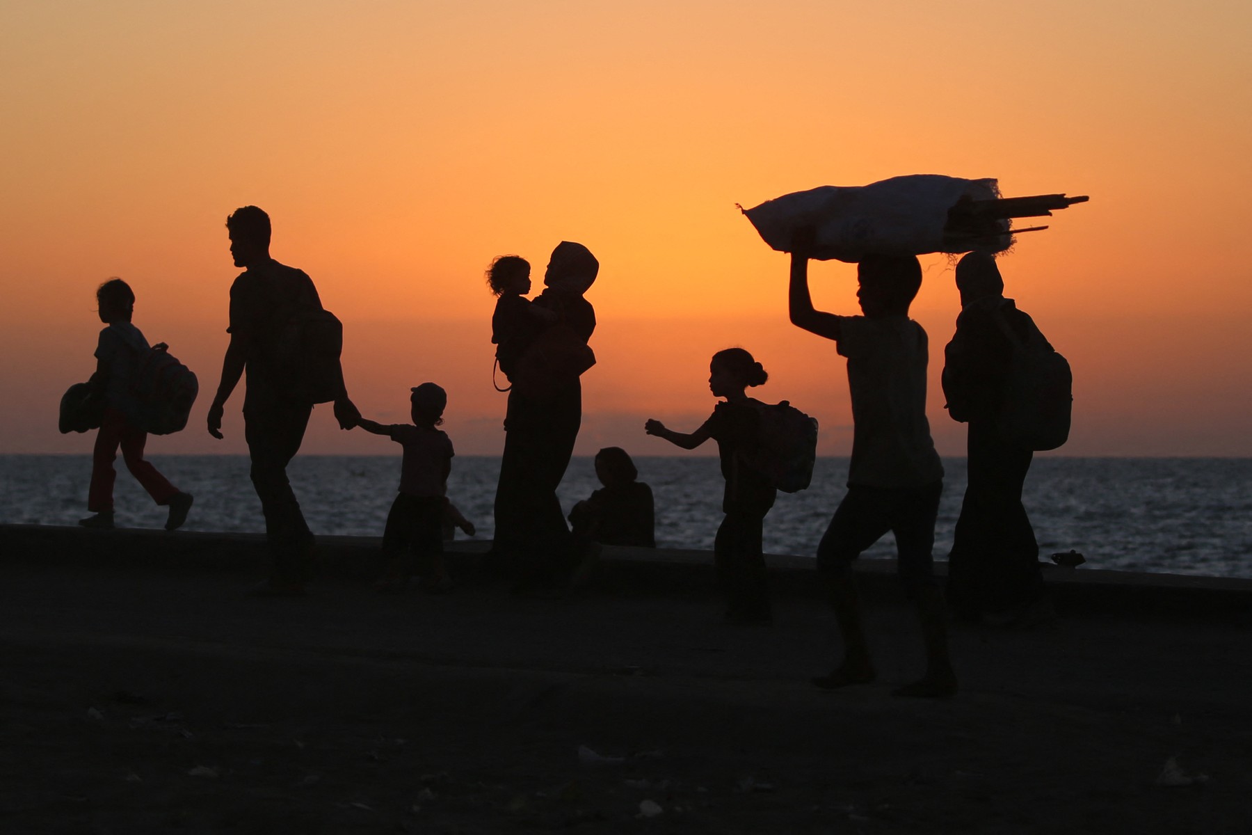 Displaced Palestinians move with their belongings southwards on a road in the Nuseirat