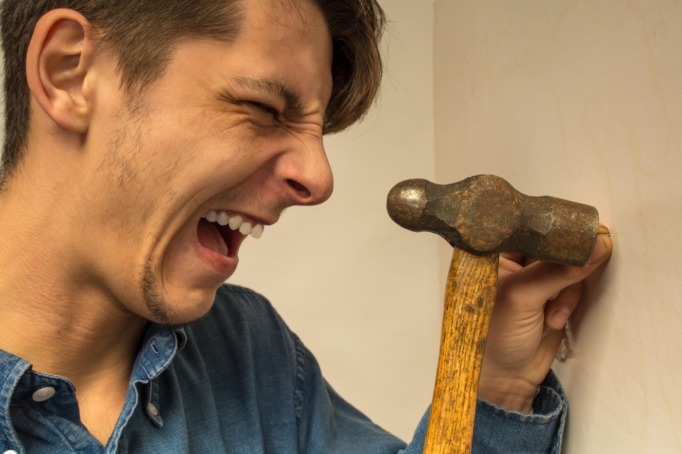 moški zabija žeblje in se udari po prstih