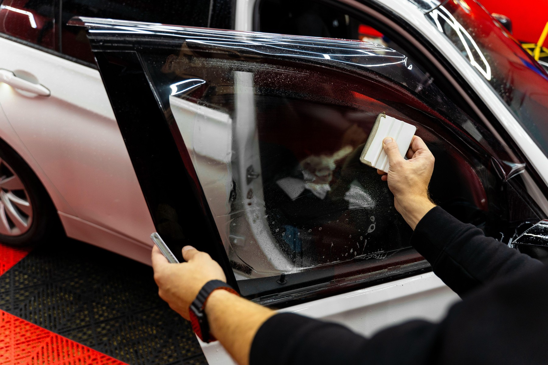 Detailer apply dark tint film to car side windows
