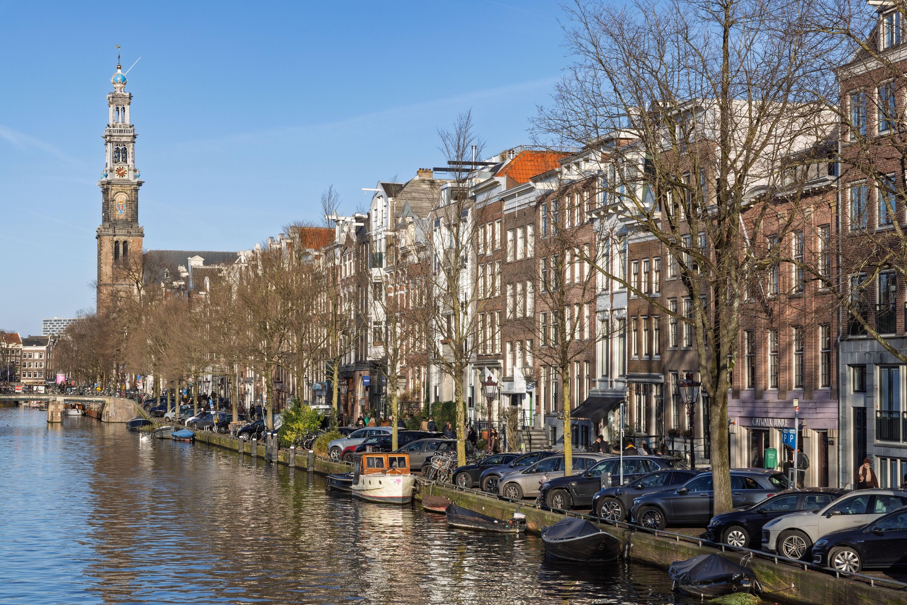 The iconic Westerkerk tower overlooking the Prinsengracht canal, lined with historic merchant houses, bare trees, and parked cars. Amsterdam Netherlands, 28 december 2025,Image: 1066234386, License: Royalty-free, Restrictions: , Model Release: no
