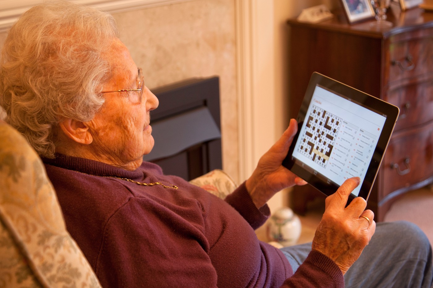 starejša ženska na tablici rešuje križanko