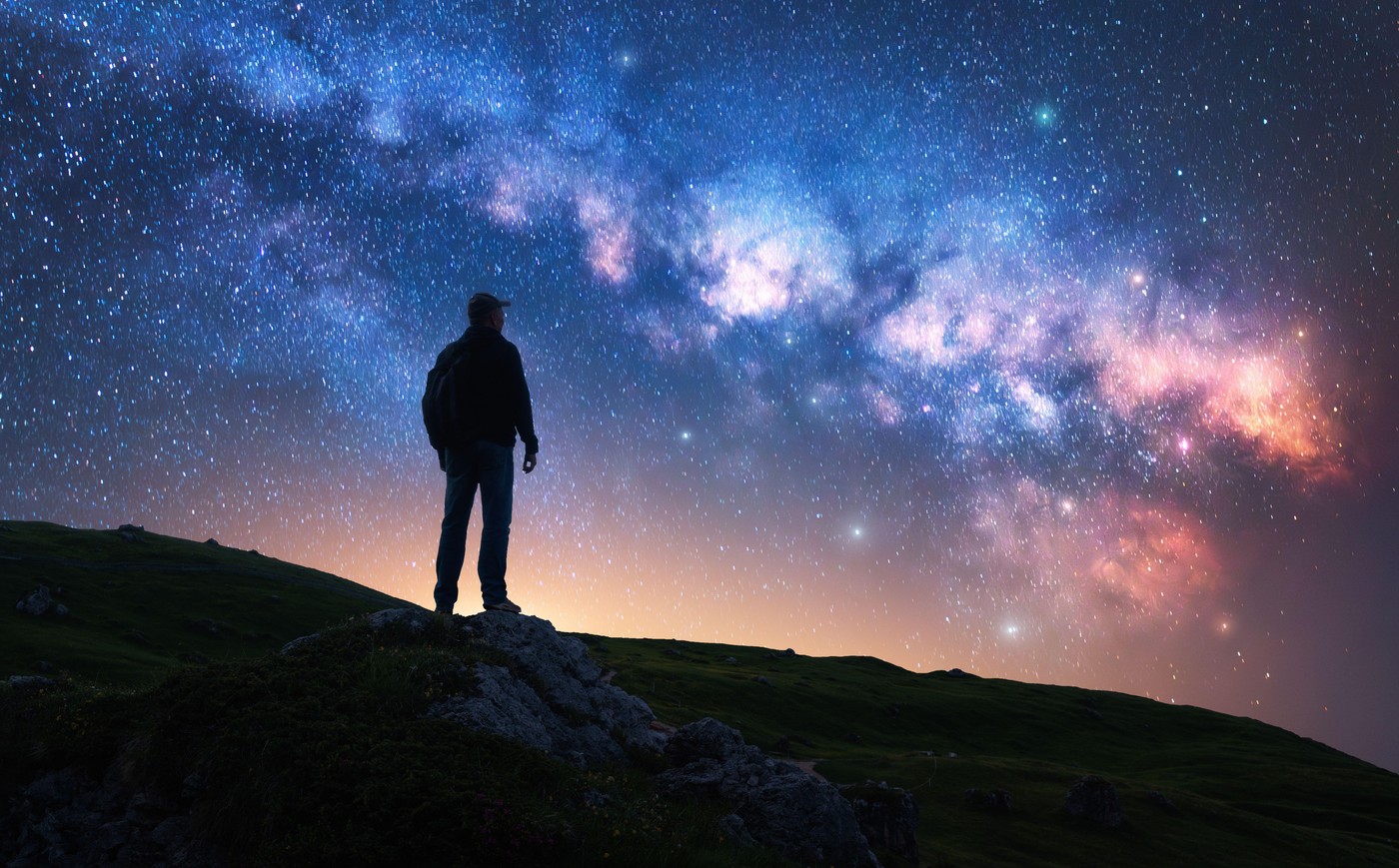 moški na vrhu gore pod žarečo Rimsko (mlečno) cesto, galaksijo na nočnem nebu