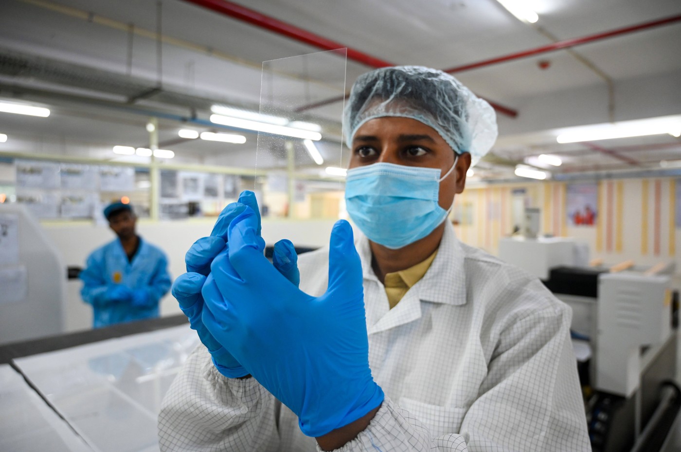 delavec v steklarni pregleduje kvaliteto kaljenega stekla