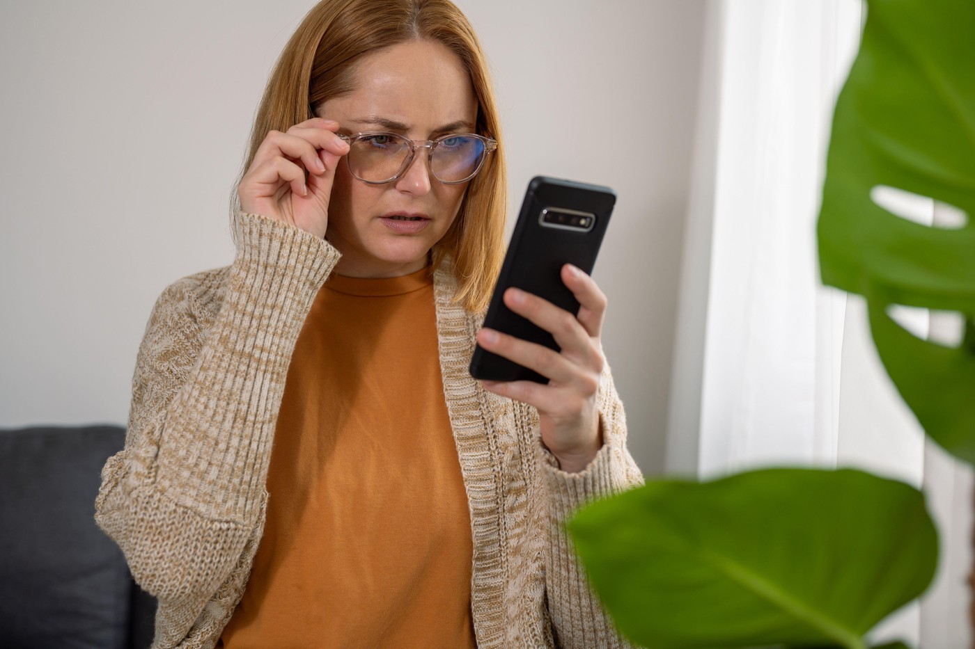 ženska z mobilnim telefonom in očali presenečena vznemirjena osupla