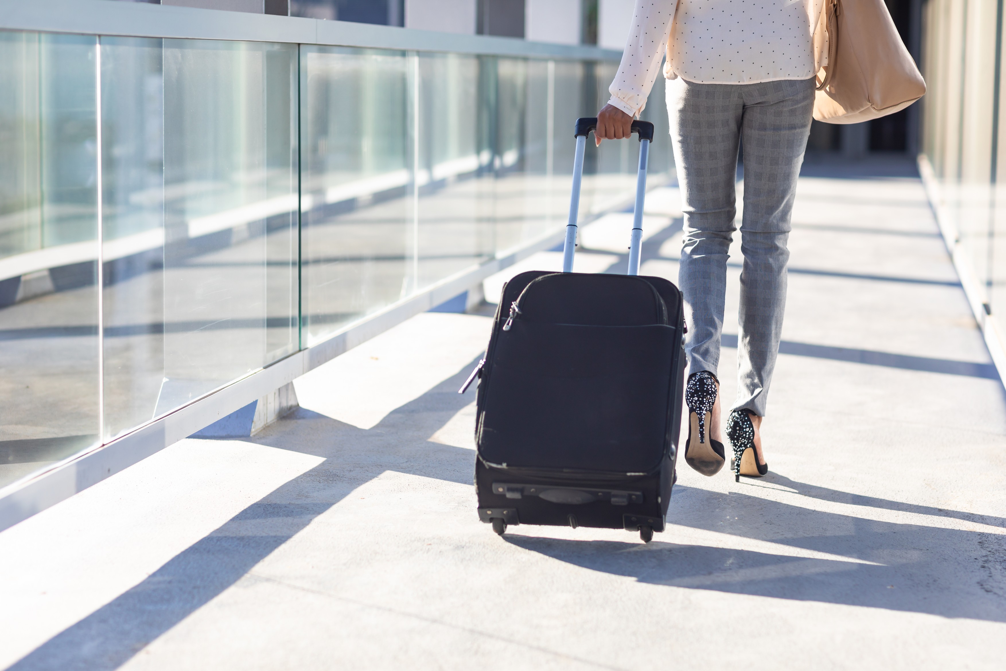 Low section of young biracial businesswoman walking with luggage in corridor at airport on sunny day. unaltered, occupation, business travel and transportation concept.,Image: 691141843, License: Royalty-free, Restrictions: , Model Release: yes