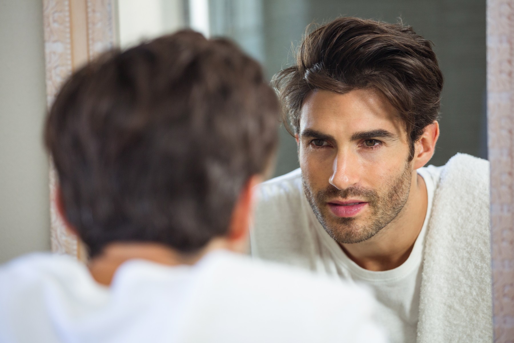 Young man looking himself in bathroom mirro
