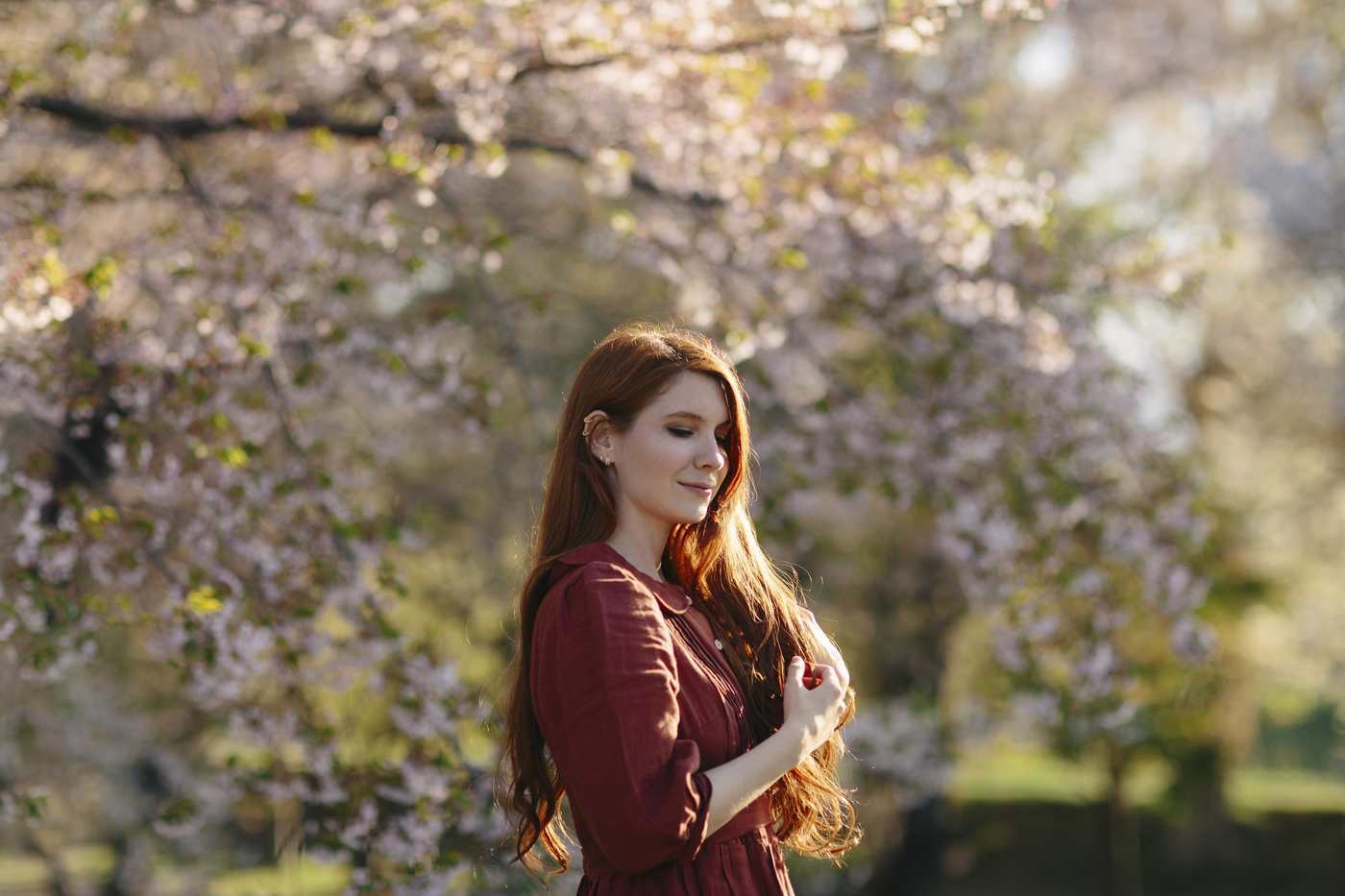 mlajša ženska s cvetočim drevjem v ozadju