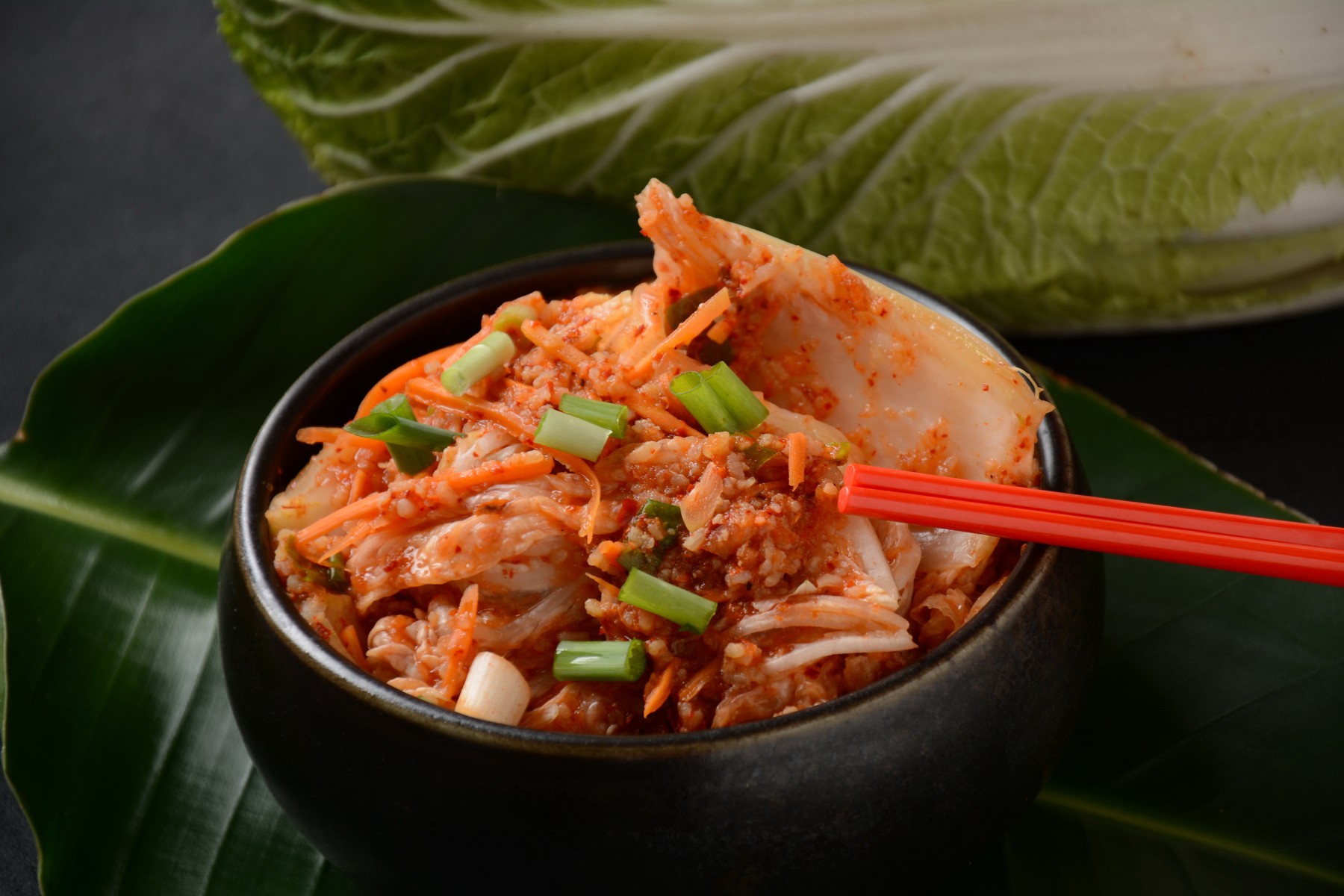Kimchi and rice in black bowl with chopstick.