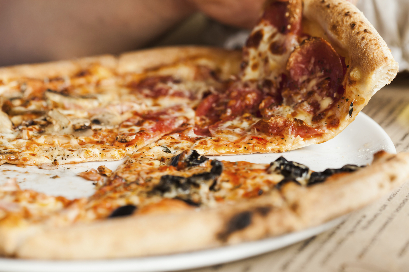 Pica na krožniku. Nekdo vzame košček pice