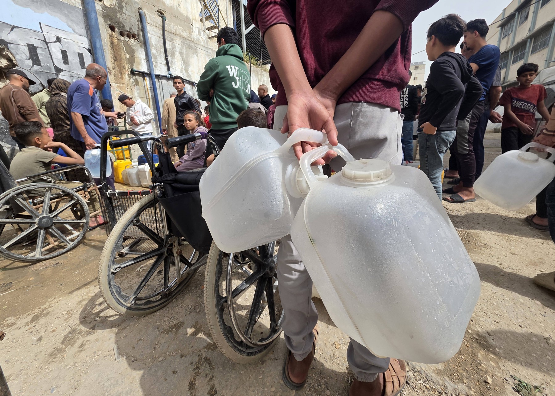 Palestinians in Khan Yunis collect water from tanker trucks and carry it