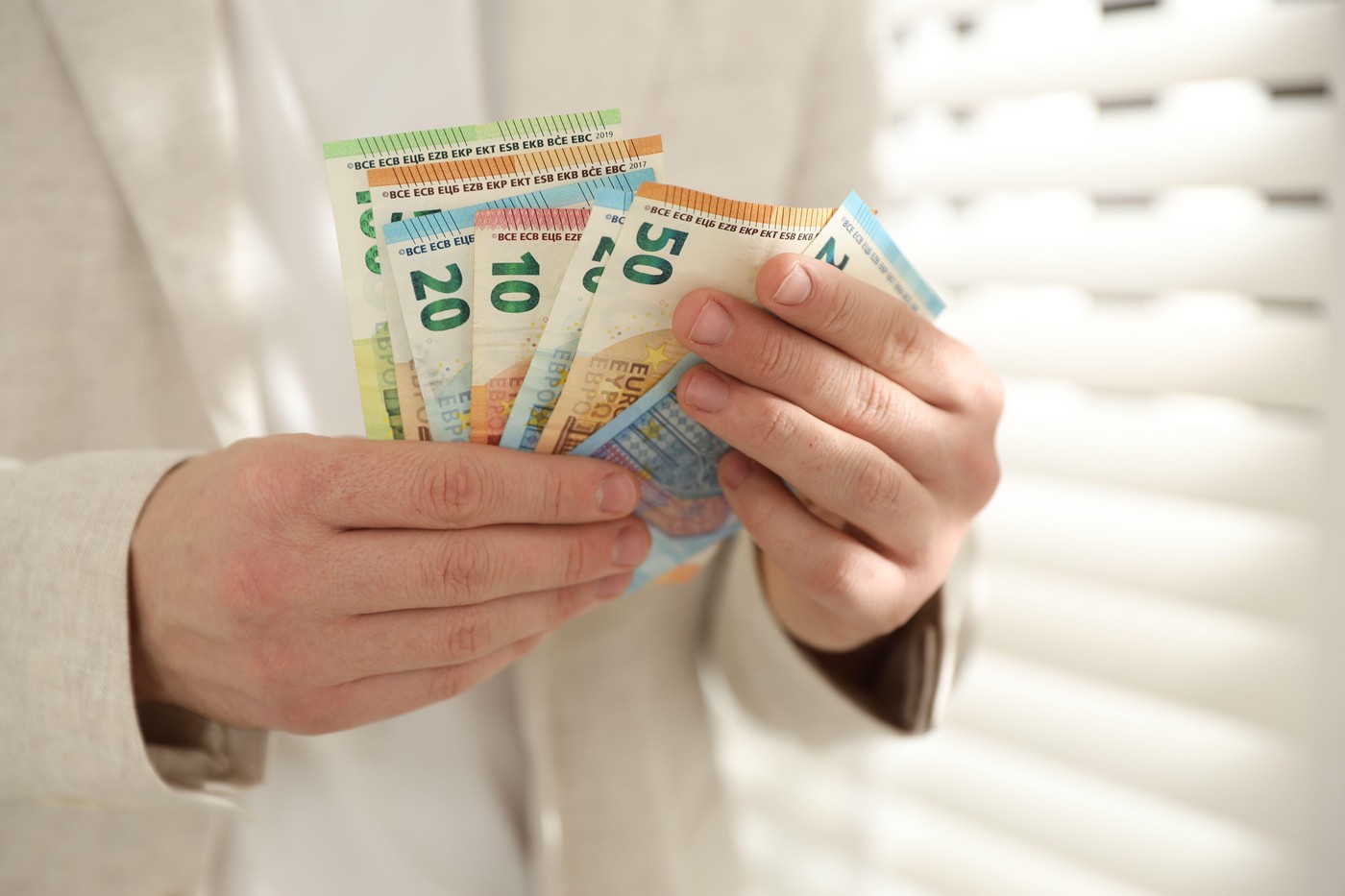 moški v rokah drži evrske bankovce