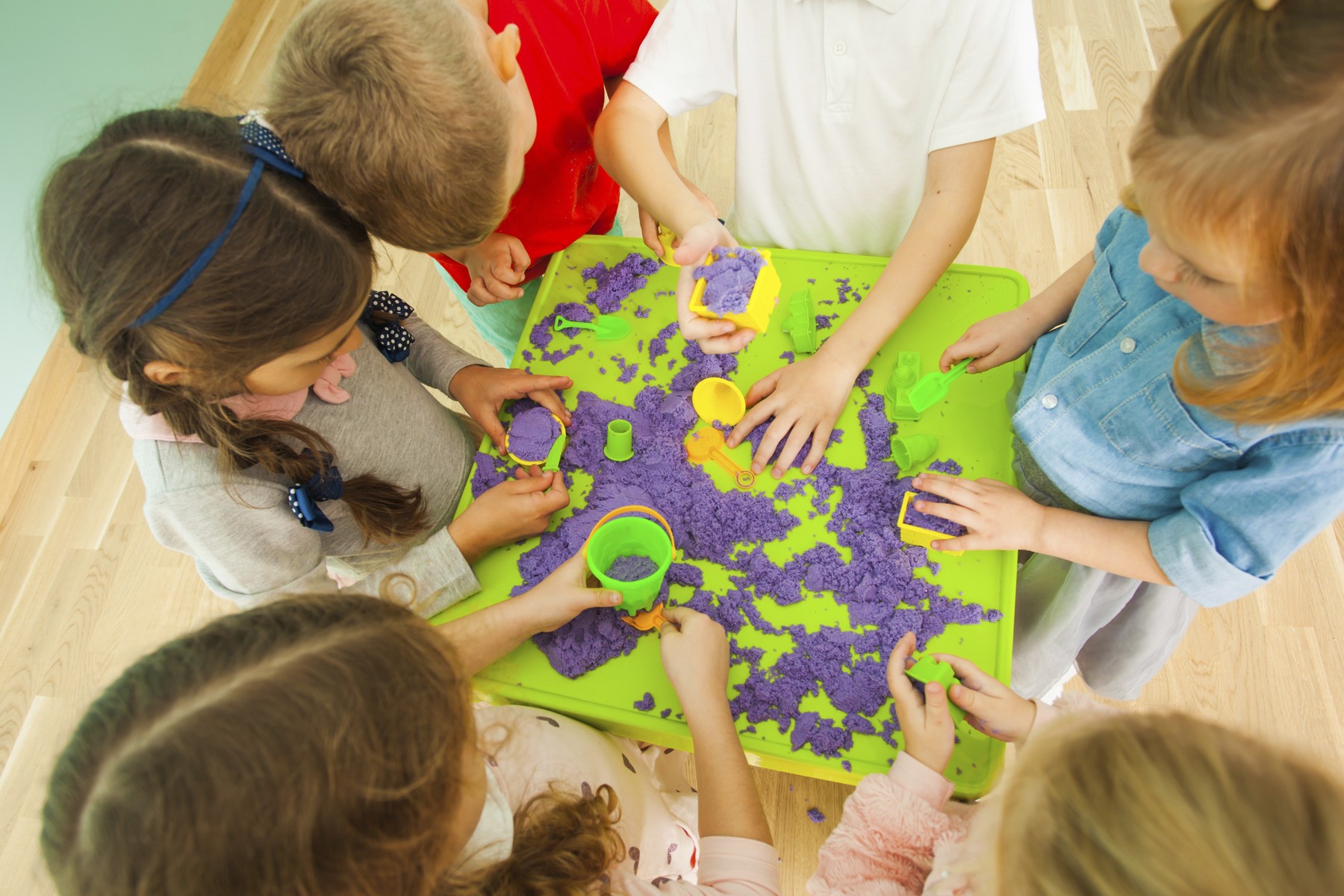 Top view of kids' creativity with color kinetic sand.