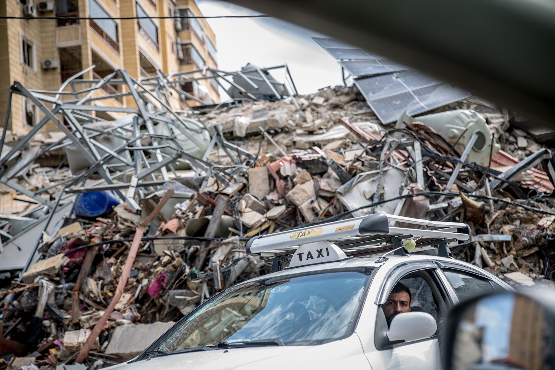 A taxi driver passes a pile of rubble in Beirut’s southern suburbs, known as Dahieyh