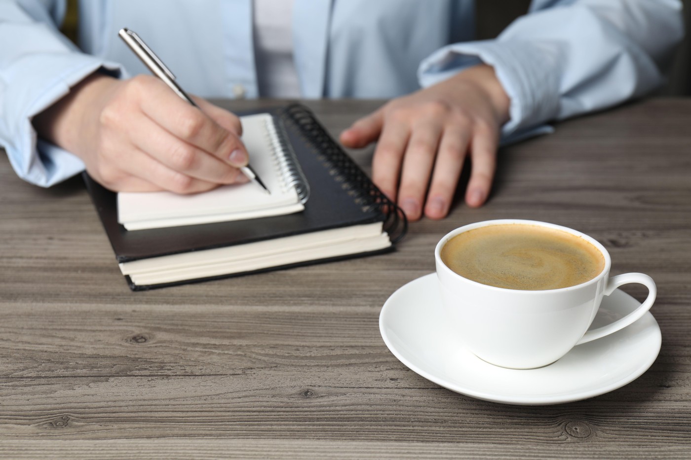 ženska piše ob skodelici kave