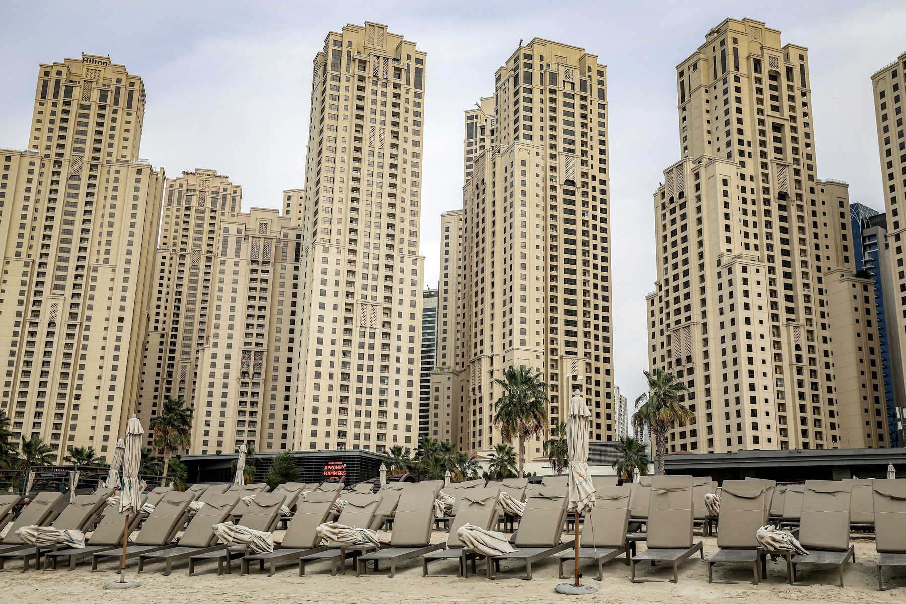 Empty beds are pictured before high-rise buildings along a beach at Jumeirah Beach Residence (JBR) in Dubai on March 11, 2026 Iran