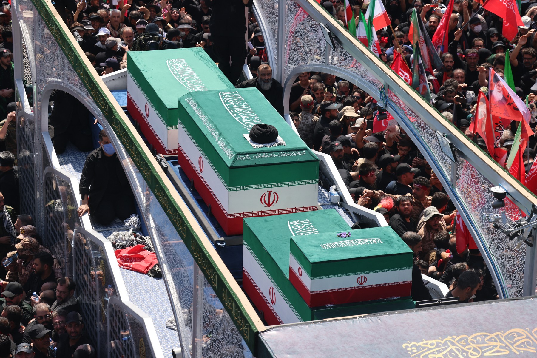 People gather along a street during the funeral procession of Iran's slain Supreme Leader Ali Khamenei.