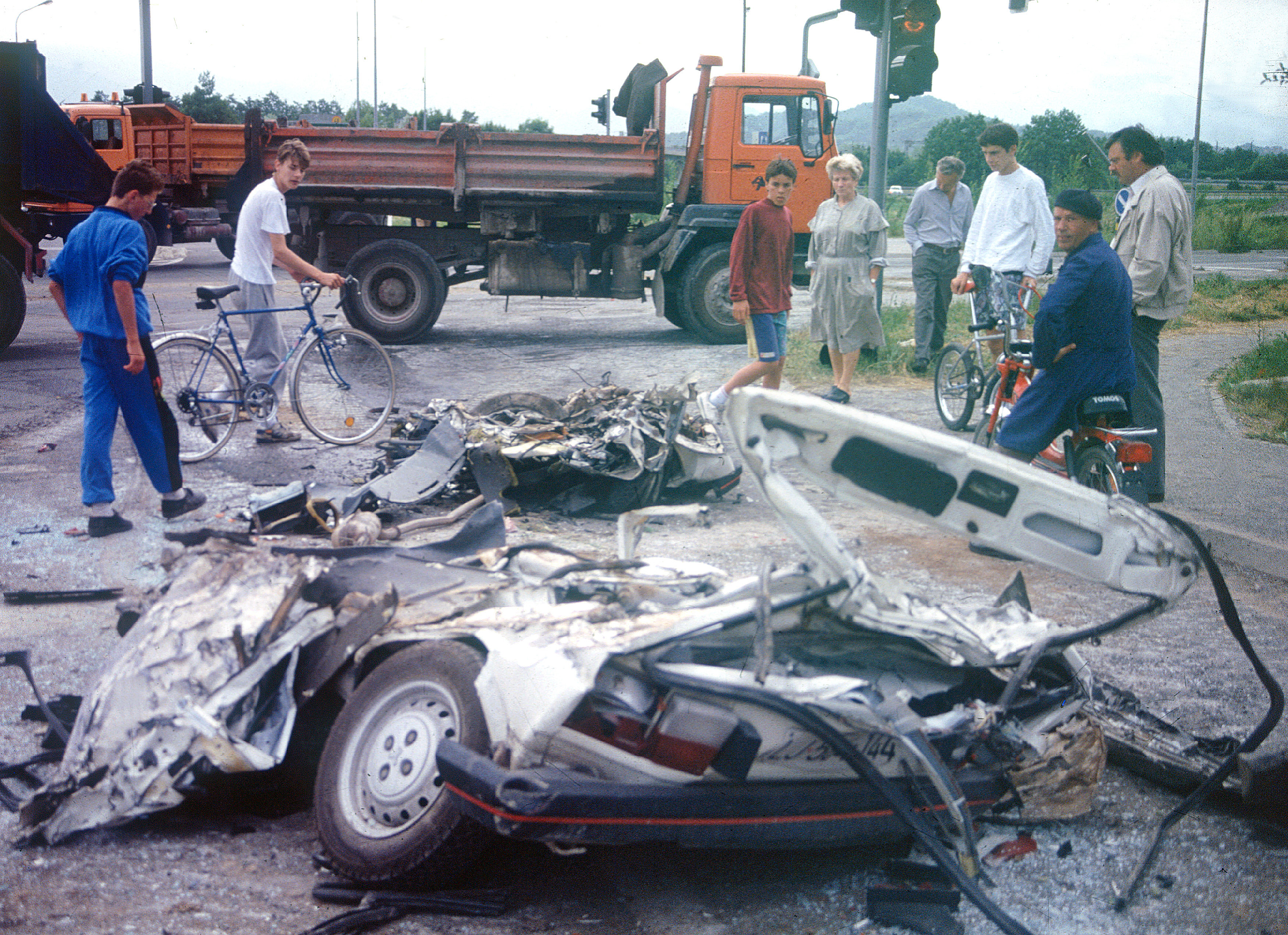 Slovenija, Lokev, 25.06.1991, 25. Junij 1991Ljudje gledajo zmeckane avtomobile, ki so jih povozili tanki JLA. Zgodovina, vojna za Slovenijo, ljudje, radovednostFoto: Bobo