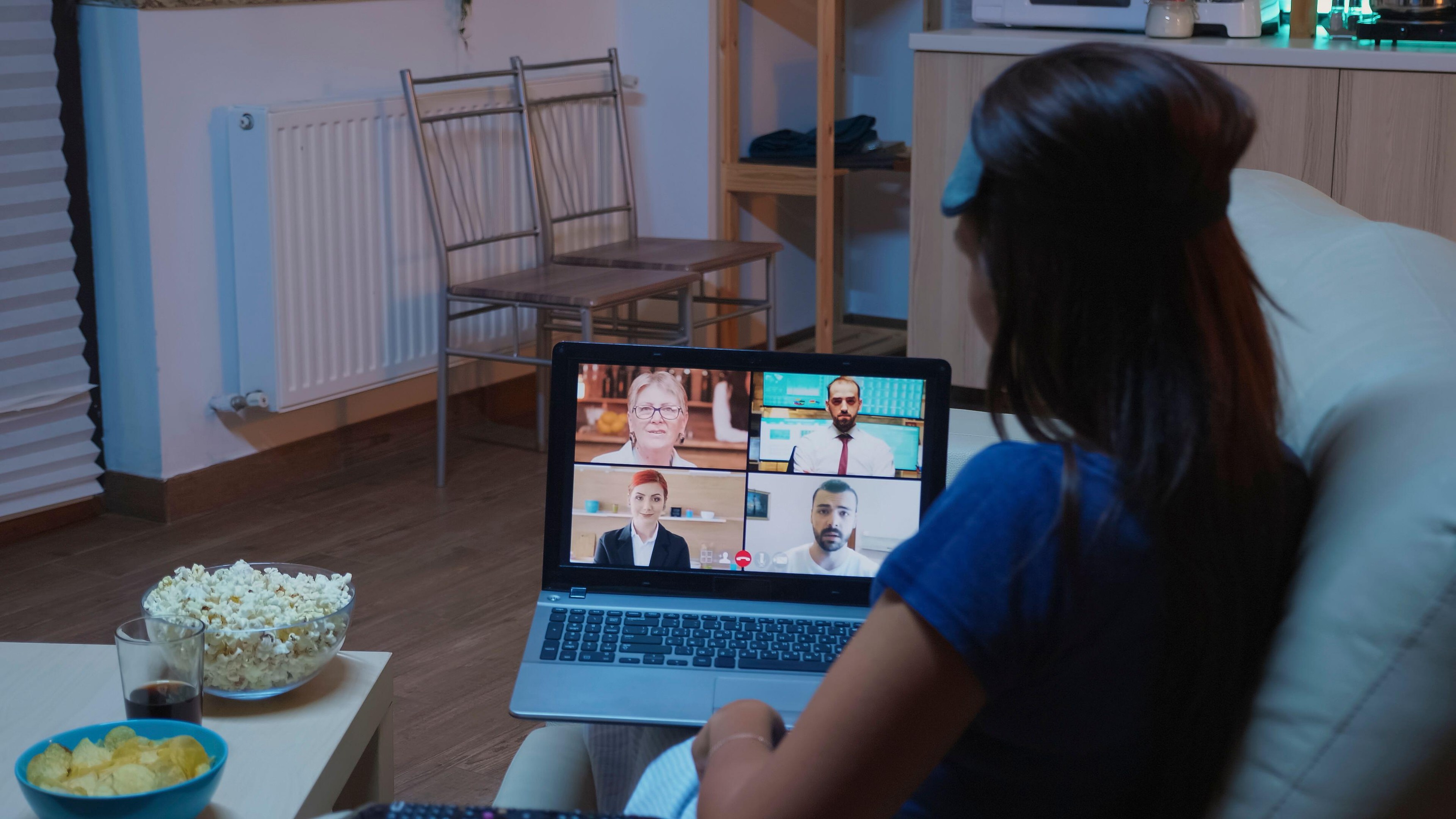 In a home living room, the woman joins an online meeting with colleagues or partners as the laptop webcam and home workspace support the discussion.,Image: 1122239592, License: Royalty-free, Restrictions: , Model Release: no
