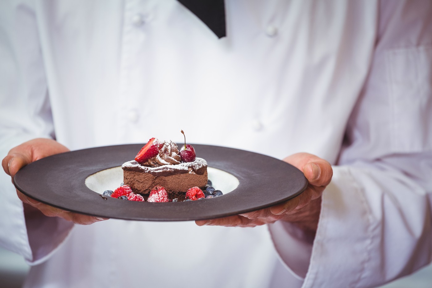 chef drži krožnik s sladico