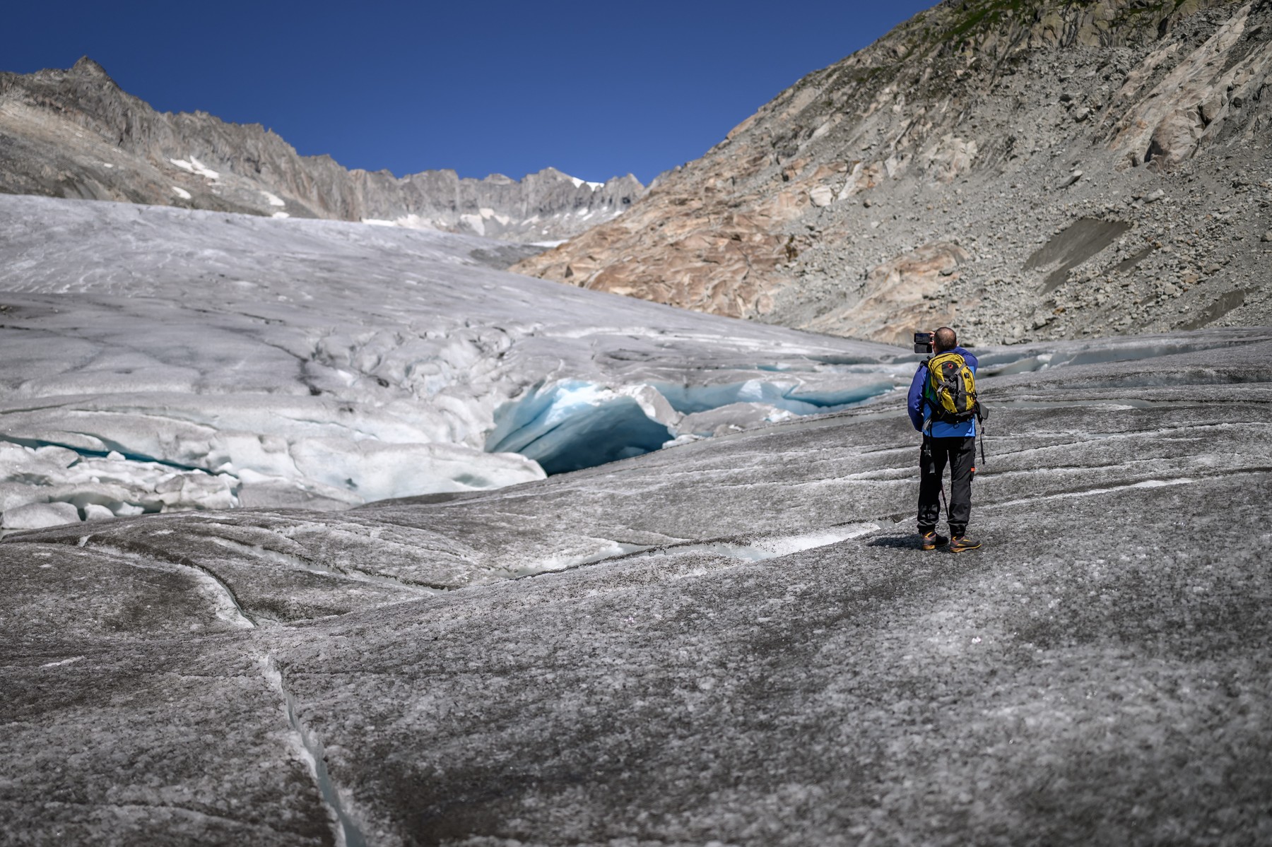 A hiker take a picture with his mobile on the lower part of the melting Rhone Glacier, Matthias Huss, head of the Swiss Glacier Monitoring Network