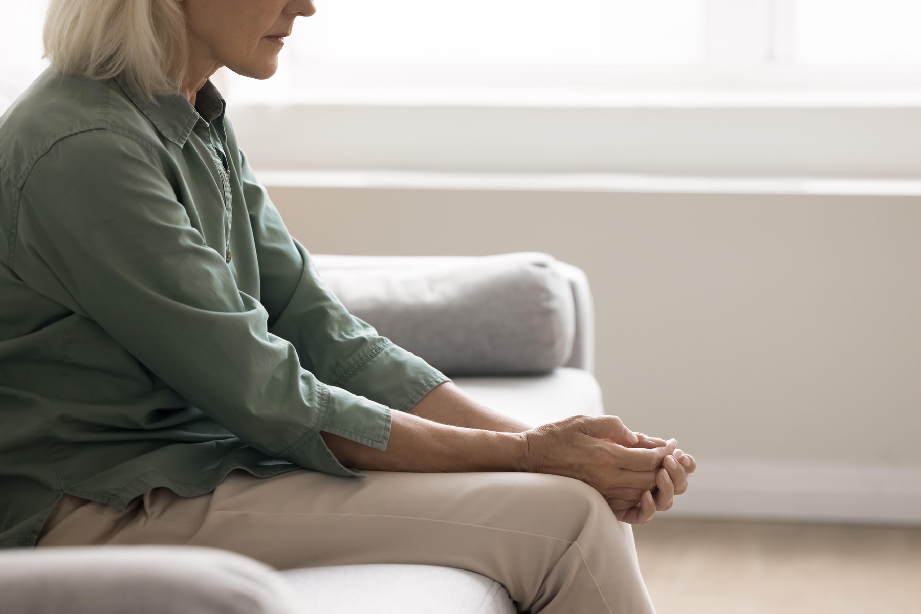 Aging problems. Close up cropped shot weak vulnerable elderly woman sit on sofa