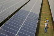 FILE PHOTO: FILE PHOTO: Workers clean photovoltaic panels inside a solar power plant in Gujarat