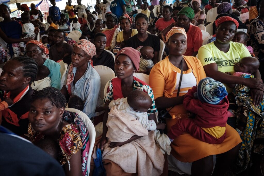 Ženske v Keniji s svojimi otroki poslušajo predavanje o cepivu proti malariji