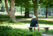 Upokojenec sedi na klopci v parku Tivoli