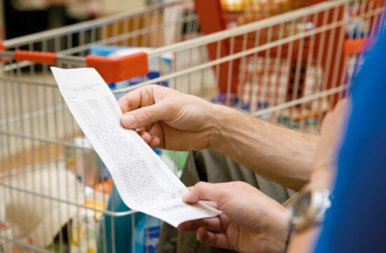 Potrošnik gleda račun pred nakupovalnim vozičkom