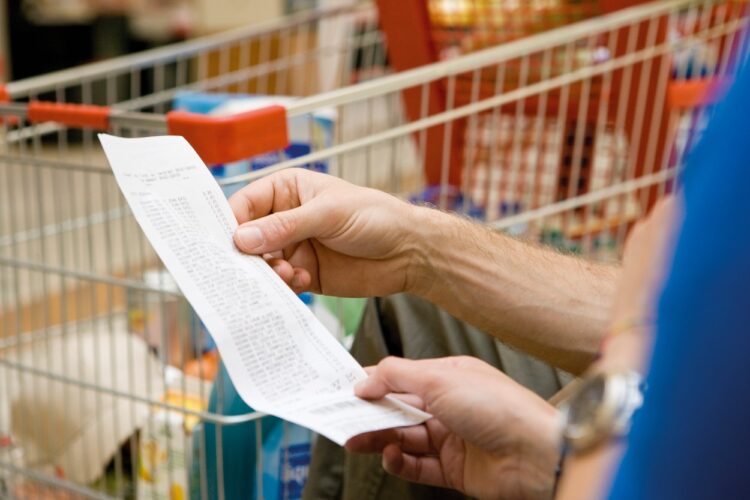 Potrošnik gleda račun pred nakupovalnim vozičkom