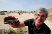 Arheolog, ki v roki drži 3500 let star delček keramike.