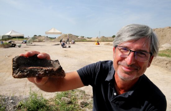 Arheolog, ki v roki drži 3500 let star delček keramike.