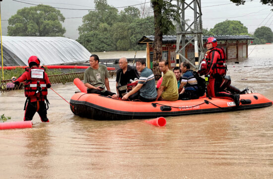 Reševalci na reševalnem čolnu rešujejo prizadete v poplavah.