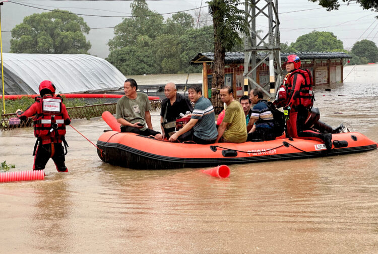 Reševalci na reševalnem čolnu rešujejo prizadete v poplavah.