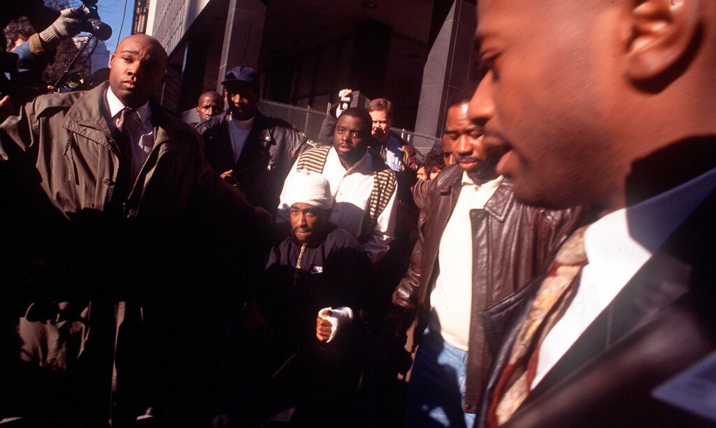 Tupac Shakur na vozičku zapušča sodišče po streljanju. 