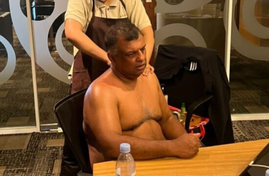Tony Fernandes na stolu, v ozadju ženska, ki ga masira