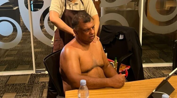 Tony Fernandes na stolu, v ozadju ženska, ki ga masira